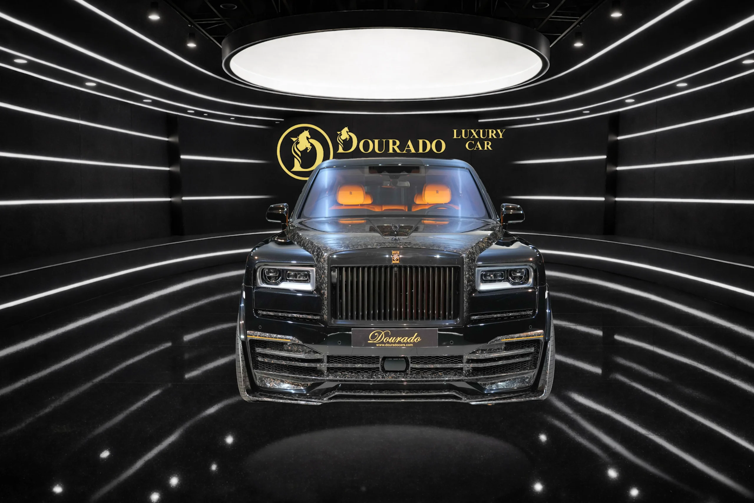 Front view of a glossy black luxury SUV centered in a dark showroom, with the gold 'Dourado Luxury Car' logo on the back wall behind it.
