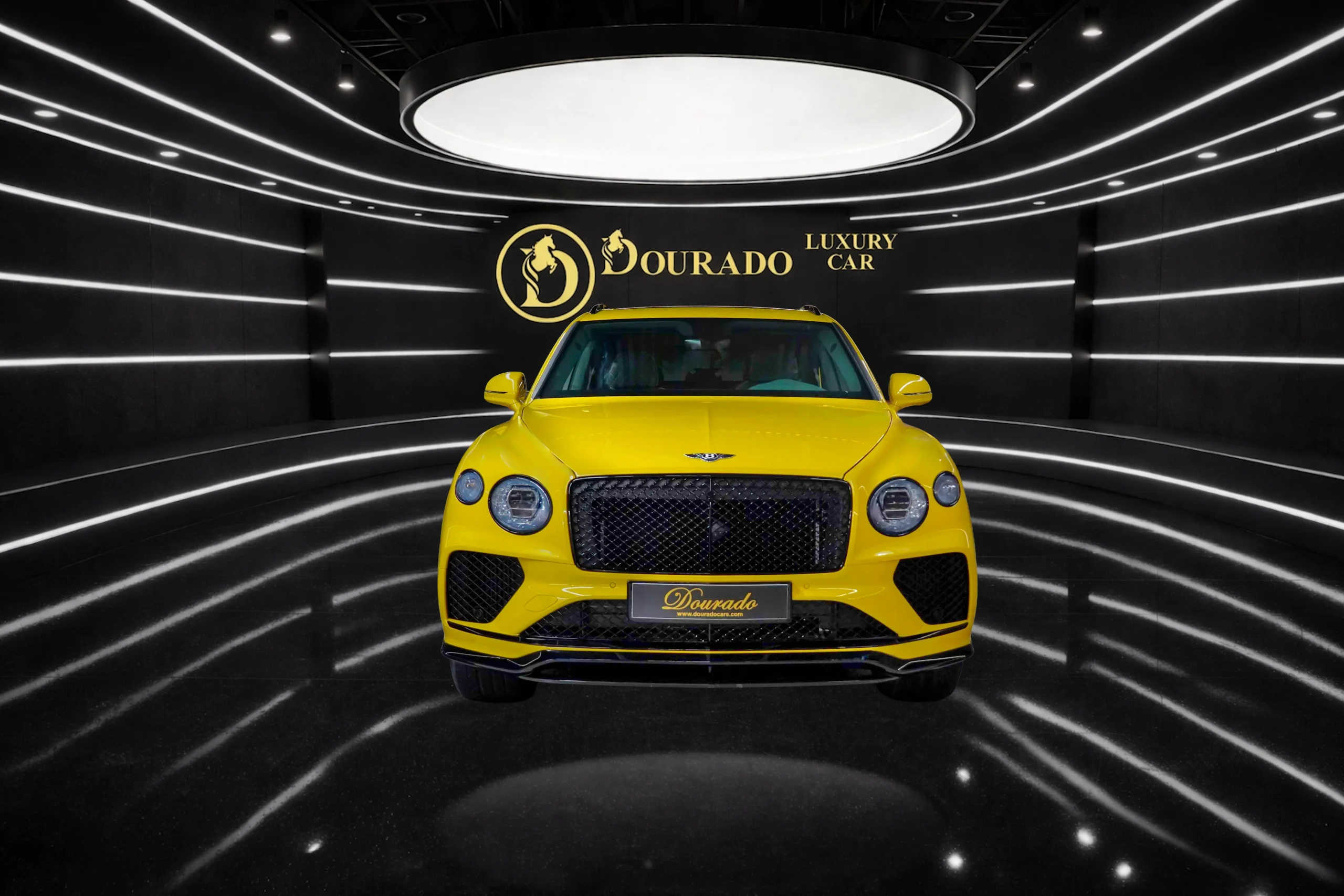 Bright yellow luxury car centered in a black showroom with white stripe lights and the gold 'Dourado' branding on the wall above it.