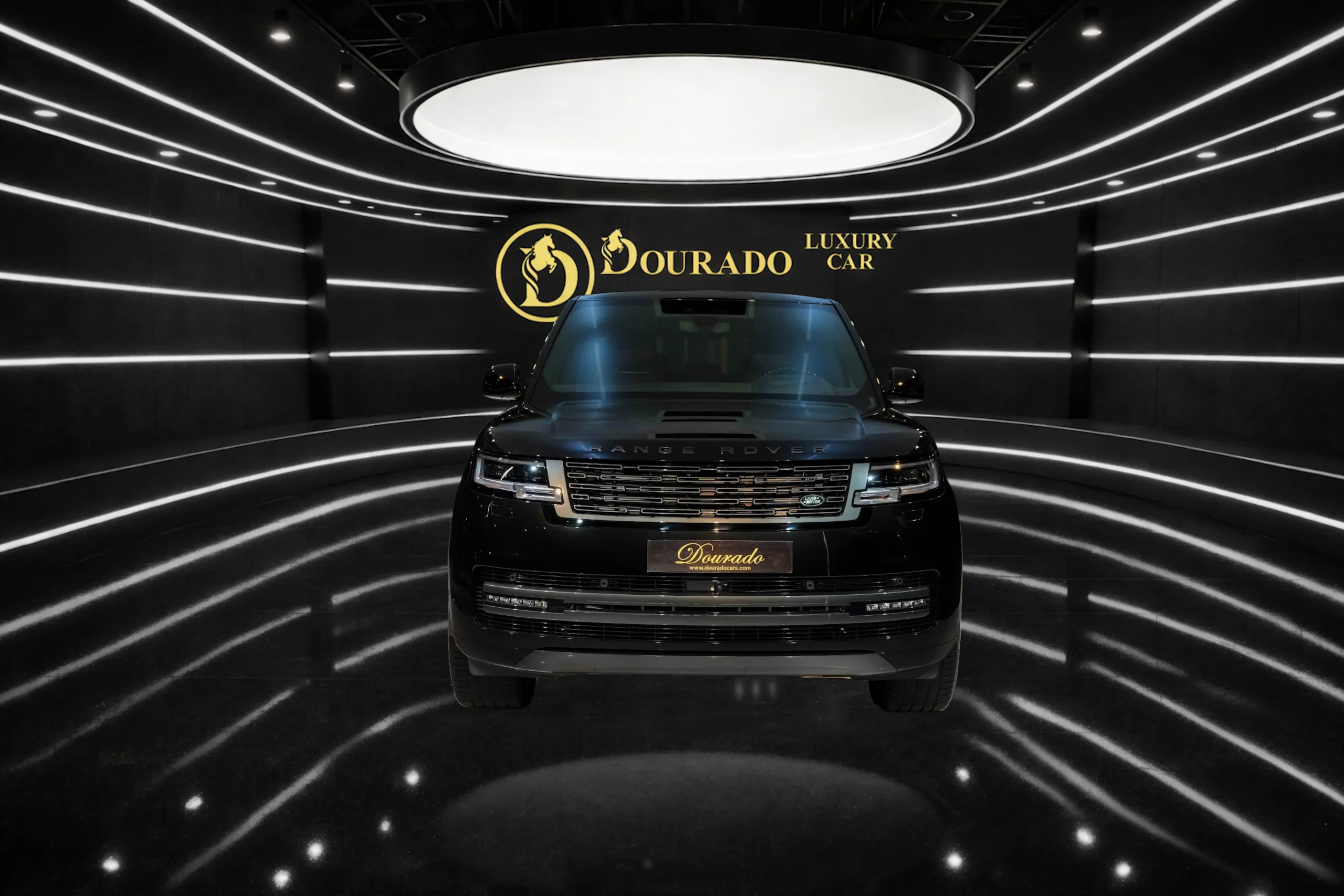 Front view of a black Range Rover in a futuristic showroom with circular ceiling light and a gold 'Dourado Luxury Car' logo in the background.
